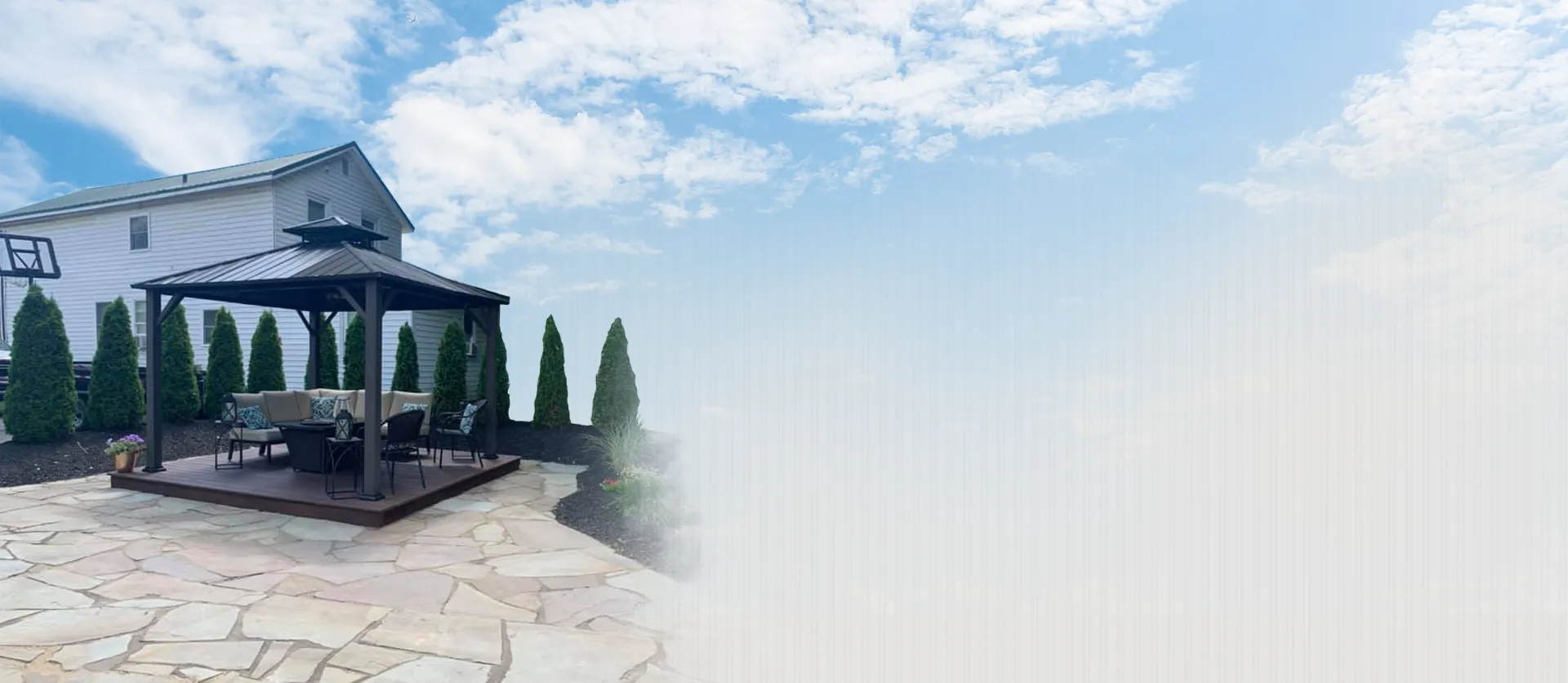 Outdoor pavilion with furniture on flagstone patio surrounded by landscaping